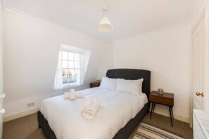 Ein Schlafzimmer mit einem großen Bett, einem Nachttisch, einem Fenster und einer Heizung.