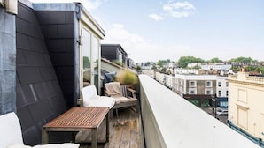 A rooftop terrace with a wooden table and chairs, a potted plant, and a view of the cityscape. - Unique 2bed Apartment, Portobello Rd (London)