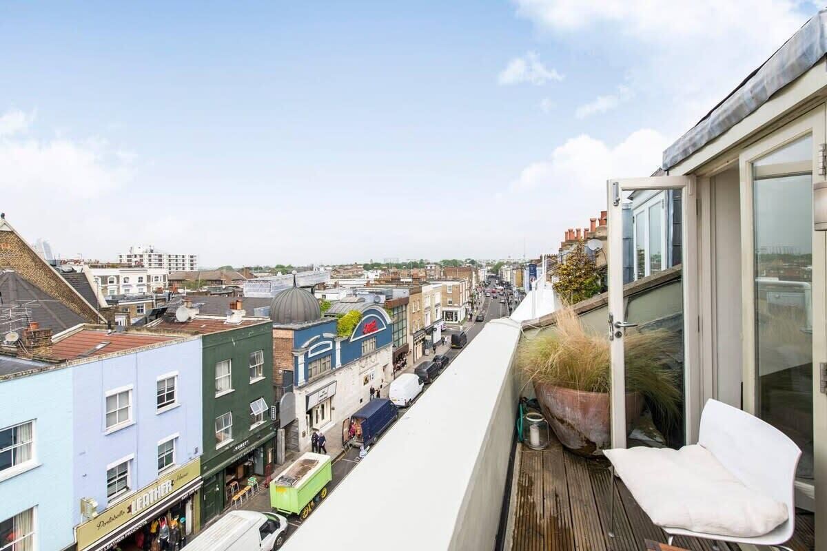 Un immeuble de grande hauteur doté d’un balcon donnant sur une rue animée.