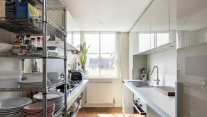 A modern kitchen with stainless steel appliances, a window with a view, and a wooden floor. - Unique 2bed Apartment, Portobello Rd (London)