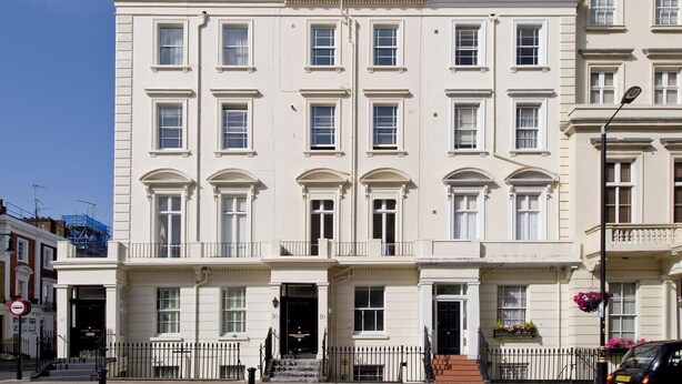 A white, multi-story building with a symmetrical facade, large windows, and a central entrance with steps.