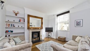 A living room with two sofas, a fireplace, a television, and bookshelves.