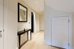 A hallway with a white door, a black console table, and a mirror on the wall.