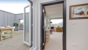 A modern interior with a wooden dining table, a kitchen area, and a large window. - Fabulous 2-bed Penthouse, Wimbledon (London)