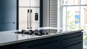 A modern kitchen with a gas stove, a built-in oven, and a refrigerator. - Fantastic 4 Bed House in Iconic Camden (London)