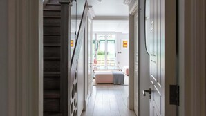 A hallway with a wooden staircase, a door with a circular handle, and a bench in the background. - Fantastic 4 Bed House in Iconic Camden (London)
