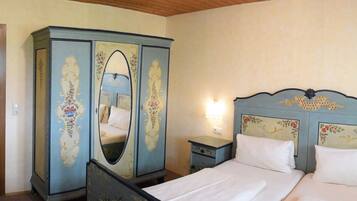 A bedroom with a bed, nightstands, a wardrobe, and a television.