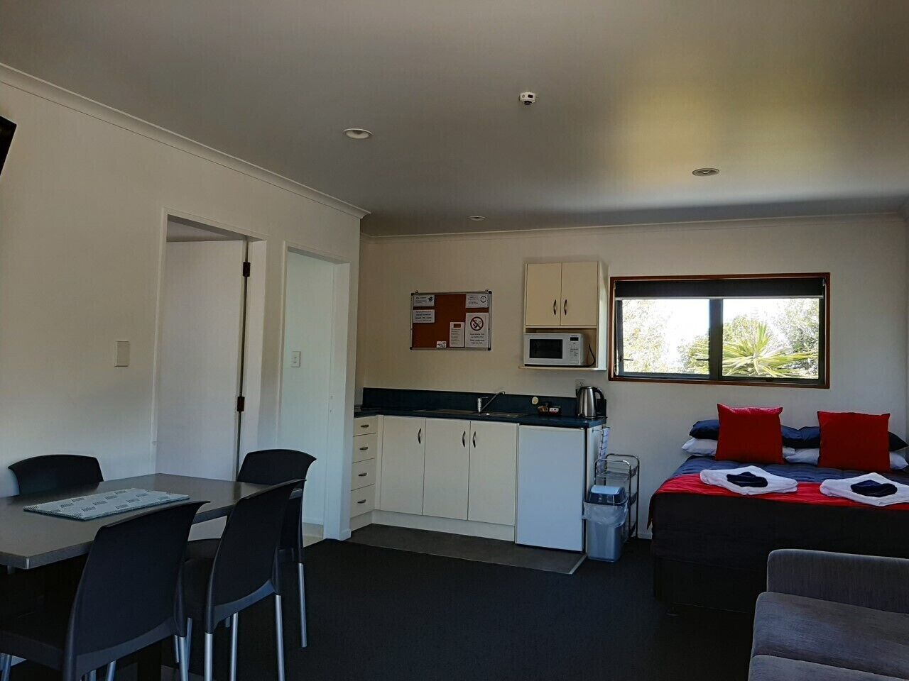 Quarto compacto com cozinha compacta, área de refeições e uma cama.