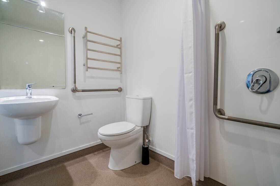 A bathroom with a white sink, toilet, and grab bars.