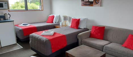 Une chambre d’hôtel avec deux lits, un canapé, une petite table, un bureau et un four à micro-ondes.