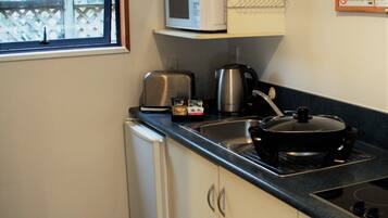 Una cocina compacta equipada con microondas, tostadora, hervidor y estufa.
