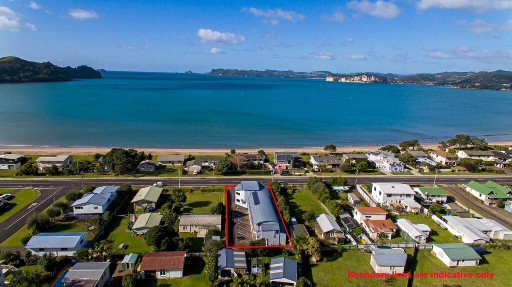 An aerial view of a coastal area with a marina, houses, and a road.