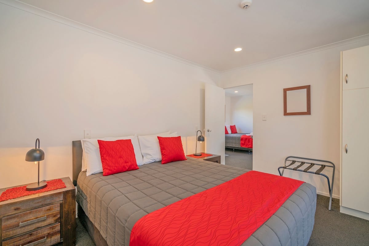 A bedroom with a bed, a nightstand, a wardrobe, and a mirror.