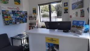 Un mostrador de recepción con una computadora, folletos y un cartel publicitario de Ocean Leopard Tours.