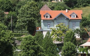 A two-story house with a red-tiled roof, surrounded by lush greenery. - hotel-21 (Schwäbisch Hall)