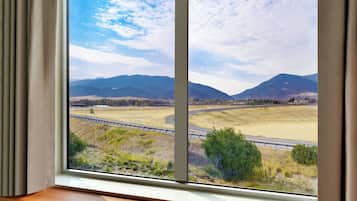 A view from a window with a view of a highway, mountains, and fields.