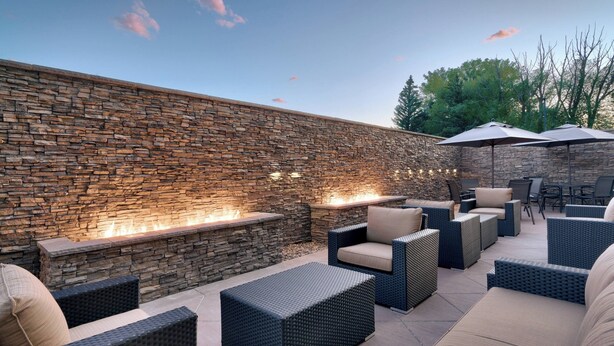 An outdoor patio area with stone walls, built-in seating, and a fire feature.