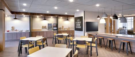 En moderne café med flere borde, stole, et køkkenområde og en bar.