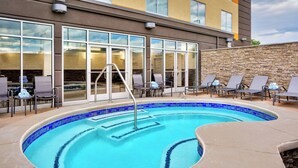 A swimming pool with lounge chairs and a stone wall.