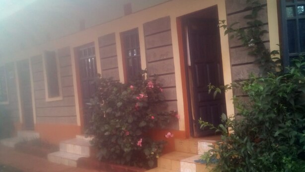 Un edificio con varias puertas y ventanas, un pequeño jardín con escalones que conducen a la entrada, y un sendero que lleva al edificio.