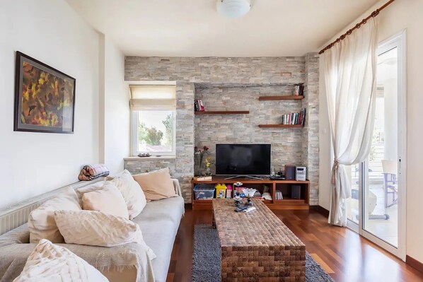 A living room with a stone wall, a sofa, a coffee table, a TV, and a sliding glass door.