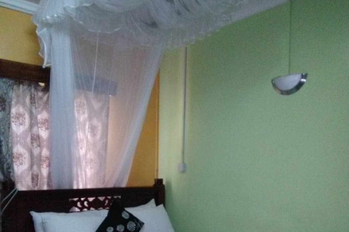A bed with a canopy, a bedside table, and a wall-mounted light fixture.
