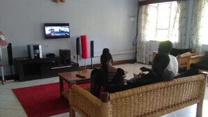 A living room with a television, speakers, and a red rug. - EL Paso Gardens Kisumu (Kisumu)