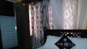 A neatly made bed with a white duvet, a black pillow with a floral pattern, and a white towel on the bed. - EL Paso Gardens Kisumu (Kisumu)