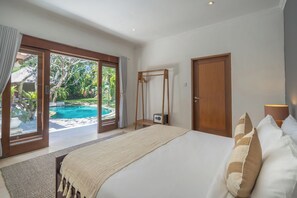 A bedroom with a large bed, a wooden wardrobe, and a view of a swimming pool. - 7-bedroom private estate in Seminyak, perfect for large groups and families. Accomodate up to 18 guests. Jasmina Estate includes daily breakfast, a private chef, airport transfers, complimentary massages, housekeeping, and a dedicated driver. (Seminyak)