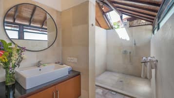A bathroom with a sink, mirror, and shower.