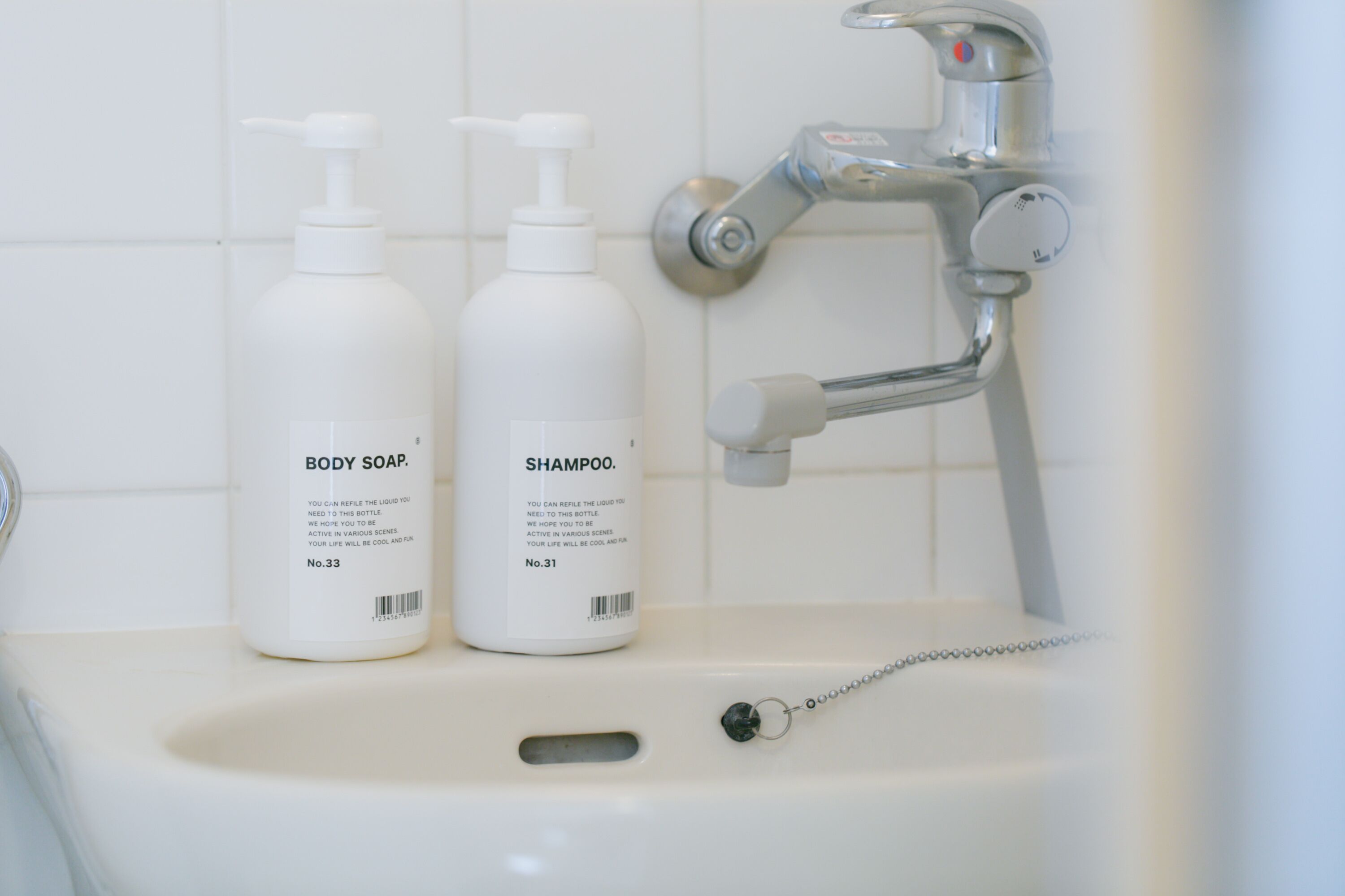 A bathroom sink with two bottles of body soap and shampoo.