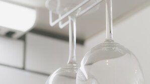 Two clear wine glasses hanging from a transparent holder. - Akebono 5-A (Naha)