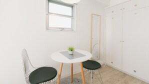 A room with a round table, two chairs, a potted plant, a window, and a wardrobe. - Akebono 5-A (Naha)