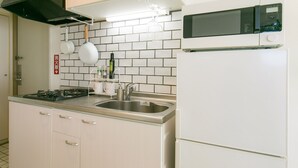 A compact kitchen with a stove, sink, and white refrigerator. - Akebono 5-A (Naha)