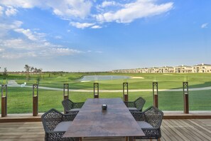Relax in a serene outdoor setting overlooking a well-maintained golf course with a pond and distant views.