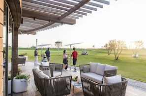 Relax on the patio with comfortable wicker sofas and chairs, surrounded by a serene golf course view.