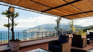 A balcony with wicker furniture, a glass table, and potted plants. - Villa Angela with private pool and sea view (Priora)