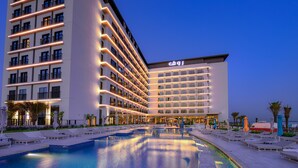 A hotel with multiple floors, a swimming pool, and outdoor seating areas. - Rove La Mer Beach (Dubai)