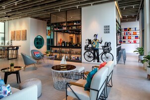 A modern lounge area with seating, a coffee table, and a bookshelf with various items.
