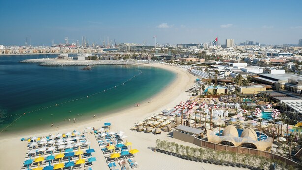 A coastal resort with beach umbrellas, a sandy beach, and a marina. - Rove La Mer Beach (Dubai)