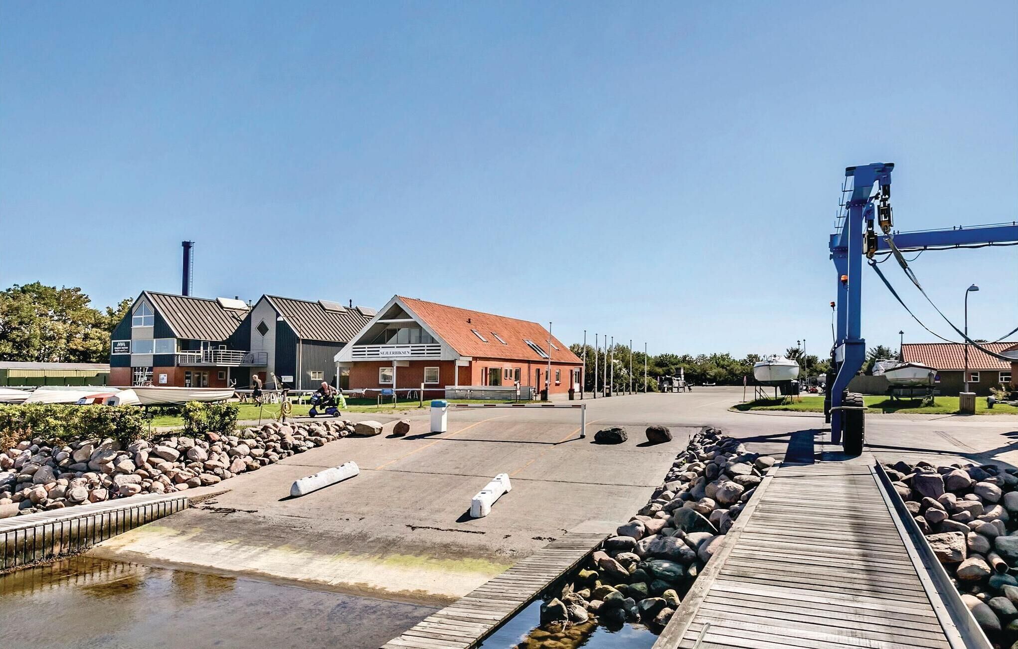 A waterfront property with a dock, a small boat, and a building with a red roof.