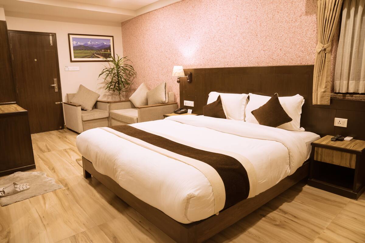 Una habitación de hotel con una cama grande, un sofá, un escritorio y una planta.