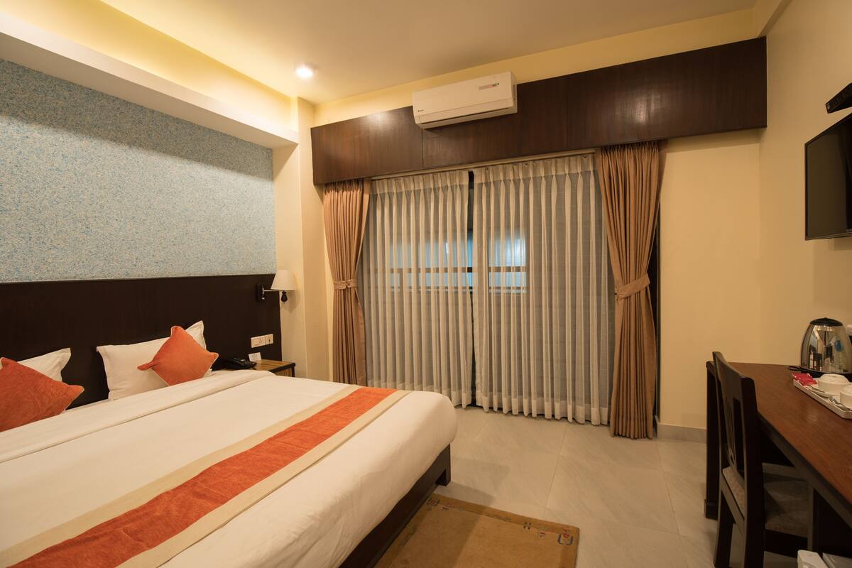 Una habitación de hotel con una cama grande, un escritorio y una televisión.