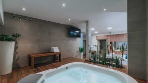 Ein modernes Badezimmer mit einer Badewanne, Holzboden, einer Sitzbank und einem Topfpflanzen.