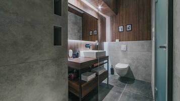 A modern bathroom with a wooden vanity, a mirror, and a toilet.