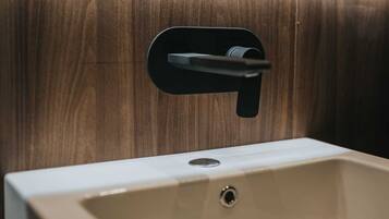 A bathroom sink with a modern faucet and a wooden panel background.