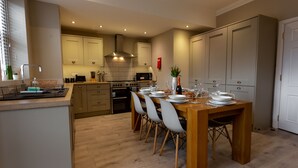 Een moderne keuken met houten kastjes, een eettafel voor vier personen en een inbouwoven.