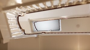 Een detail van een plafond met een inbouwspots en een ventilatierooster.