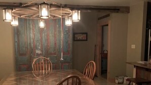 Un comedor con una mesa y sillas de madera, una araña y una puerta rústica.
