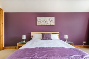 A bedroom with a bed, two bedside tables, and a wall-mounted artwork.